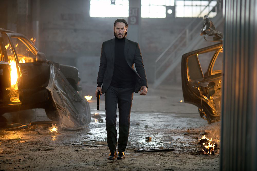 Keanu Reeves struts through bits of burning cars on the ground with locomotive breath in the scene where he kills Iosef