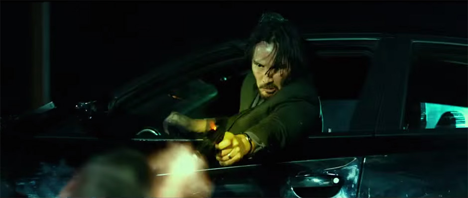 Keanu Reeves as John Wick makes a headshot out the window of his Dodge Charger
