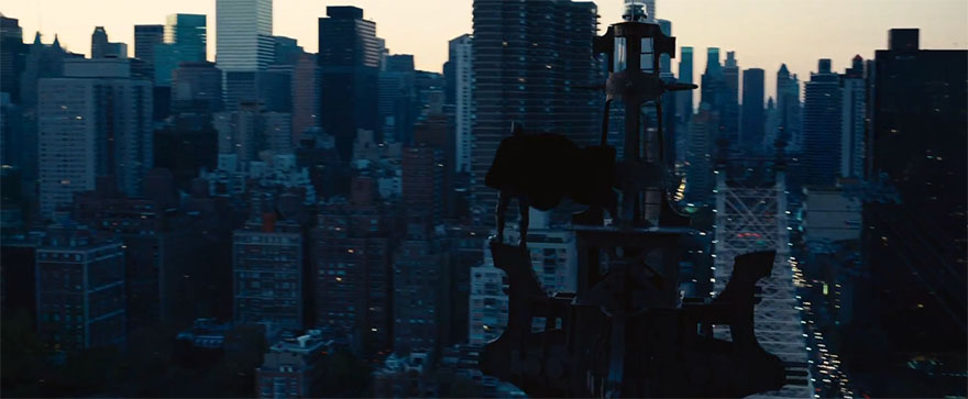 The Dark Knight Rises Batman standing on skyscraper tower with cape blowing in the wind