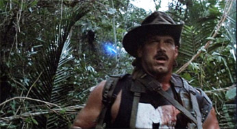 Predator movie the startled and pained look on Blain's face after the first hit to his neck as a second laser comes from behind as is about to hit him in the back
