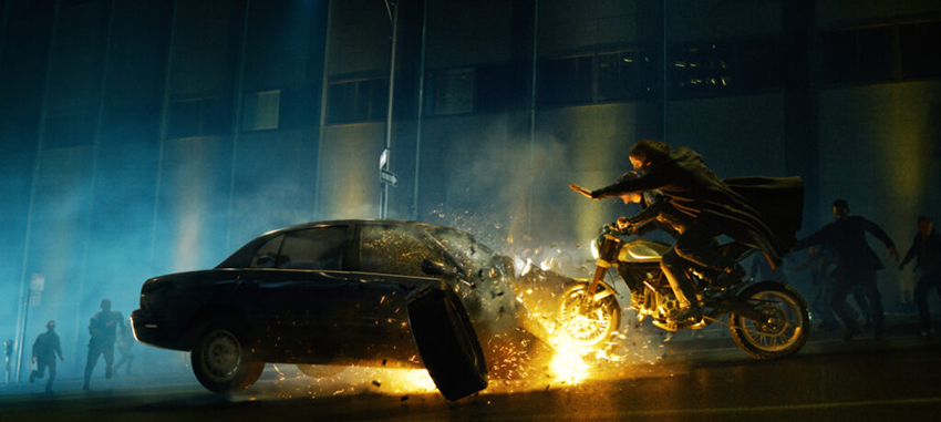 The Matrix Resurrections motocycle rides over a car stunt