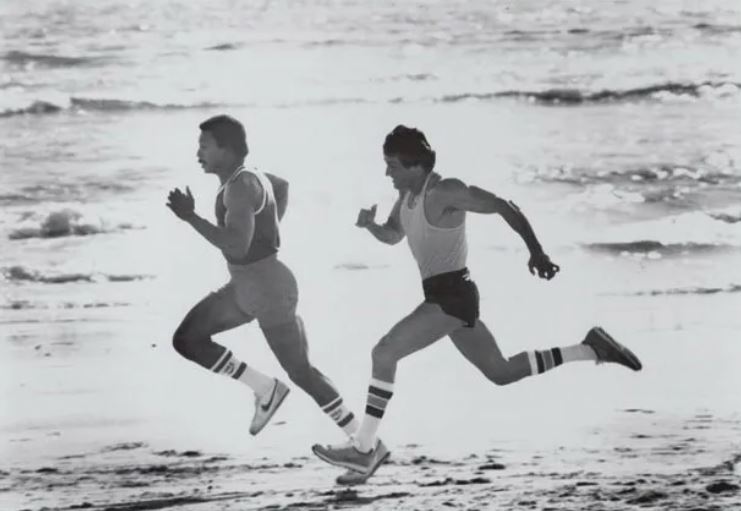 Carl Weathers and Sylvester Stallone sprint down the beach
