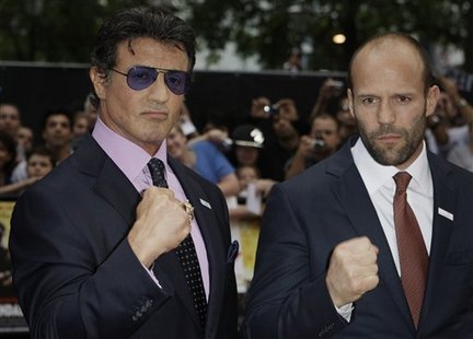 Sylvester Stallone and Jason Statham on the red carpet in suits and ties and making fists