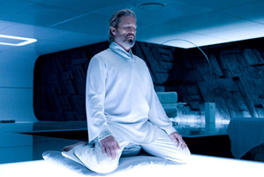 Jeff Bridges kneels on a matt in a yoga pose from Tron Legacy